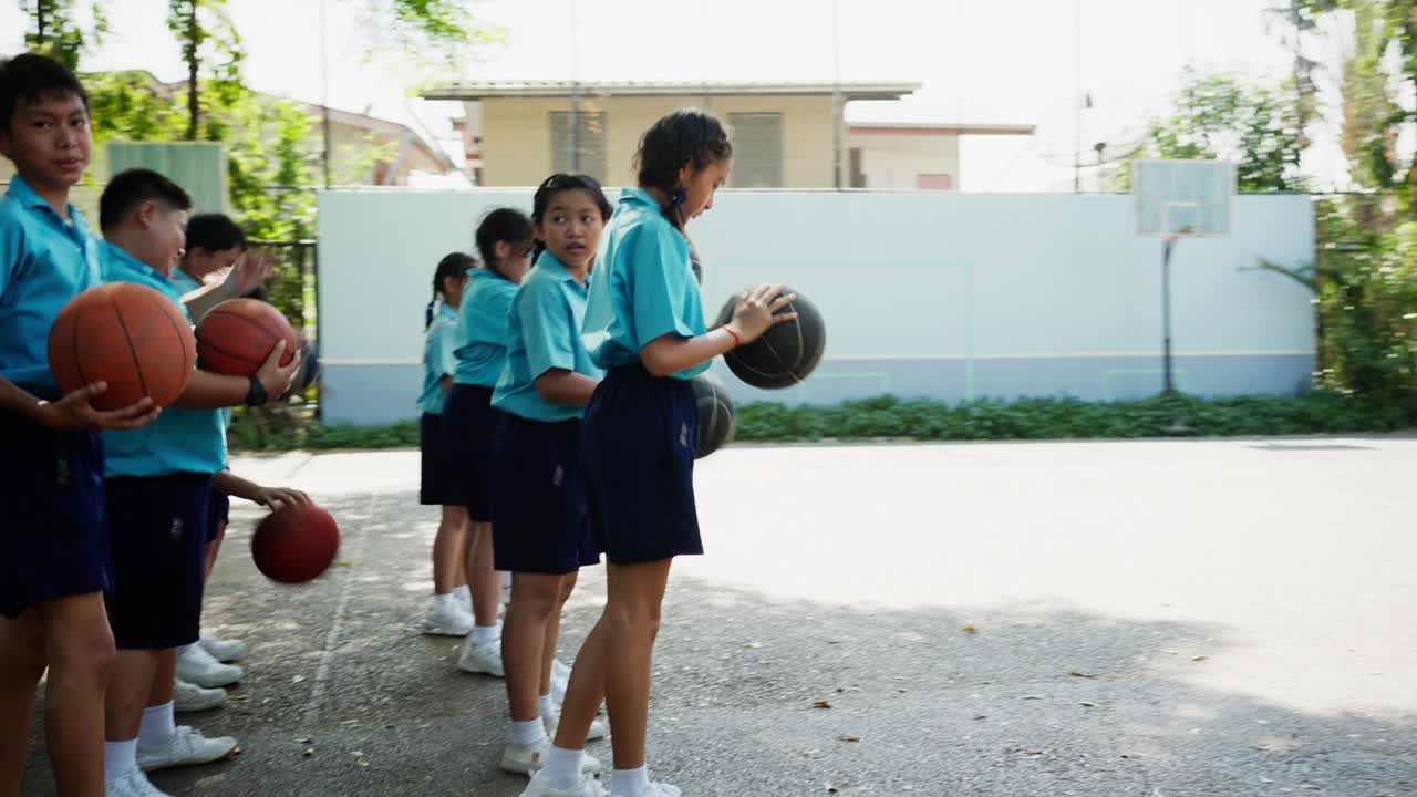 孩子们在学校操场上学习基本的篮球技术视频素材