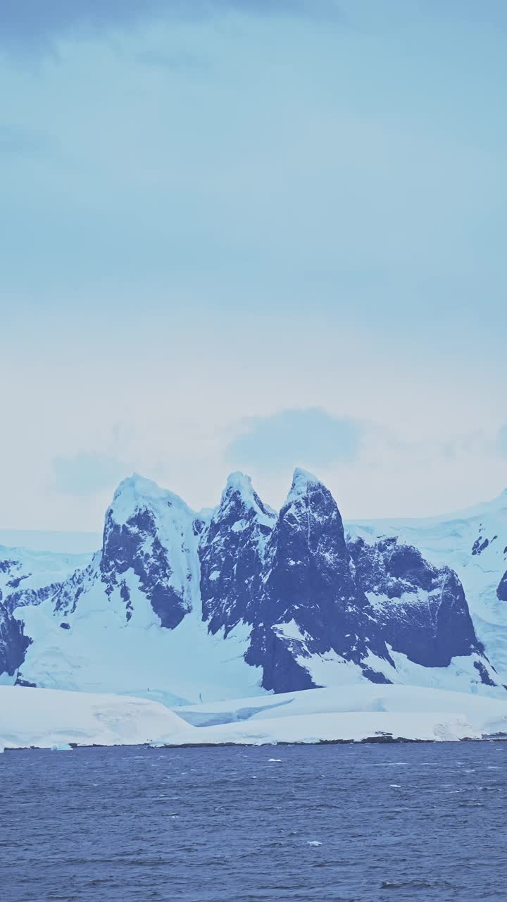 日落白雪皑皑的冬季山脉在南极洲的海岸风光，南极半岛海岸的白雪覆盖的景观在社交媒体，Instagram Reels和抖音垂直视频视频素材