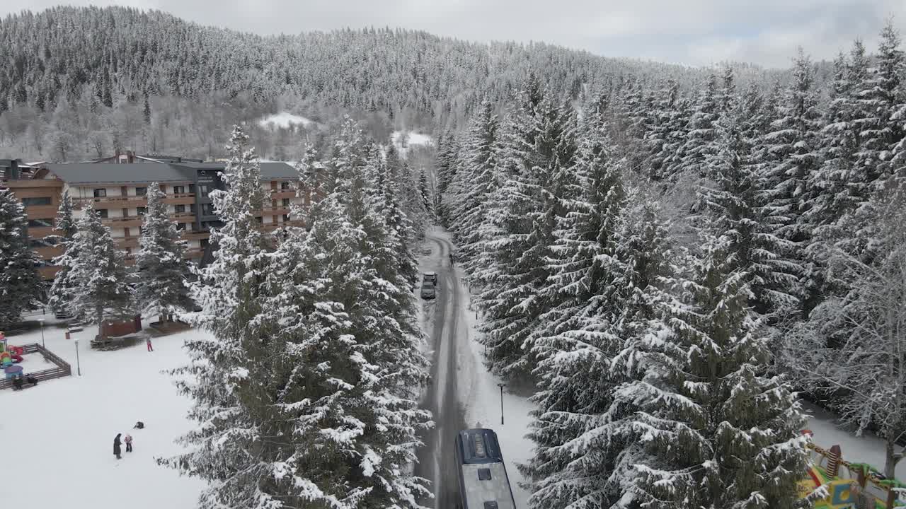 白雪覆盖的滑雪场停车场，汽车和建筑被白雪覆盖的树木包围视频素材