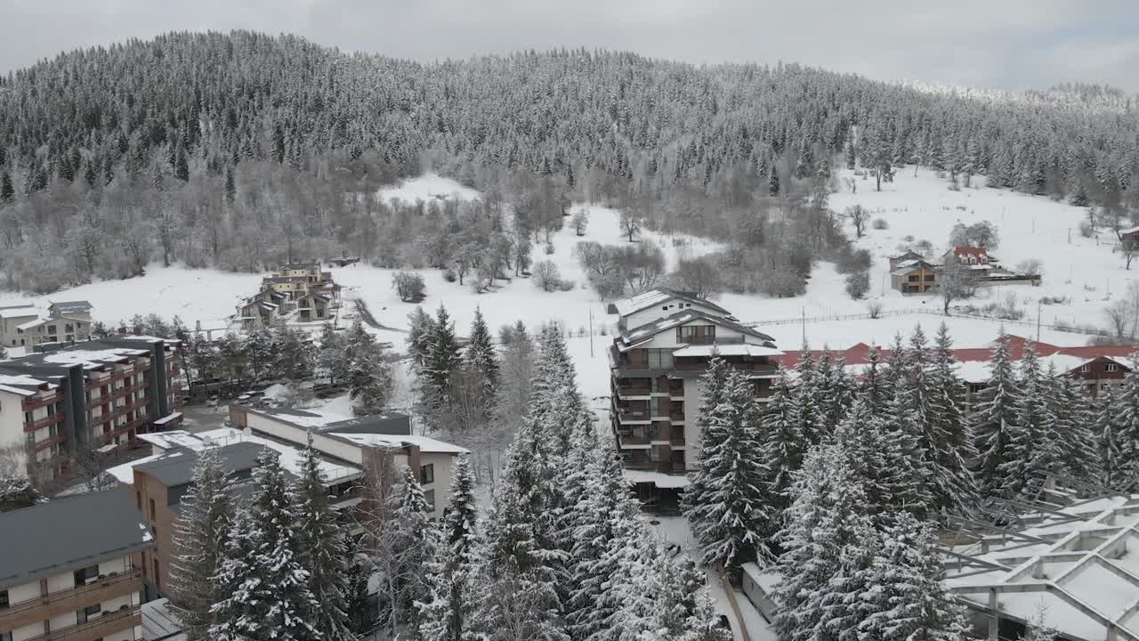 熙熙攘攘的滑雪胜地鸟瞰图，展示滑雪道和白雪覆盖的建筑视频素材