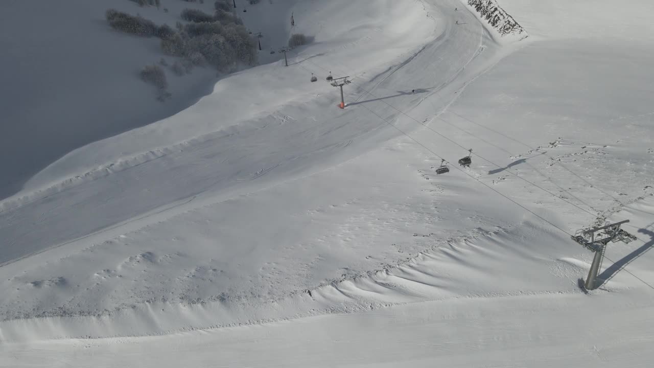 一条滑雪道蜿蜒穿过白雪皑皑的森林，邀请滑雪者探索冬季美景视频素材