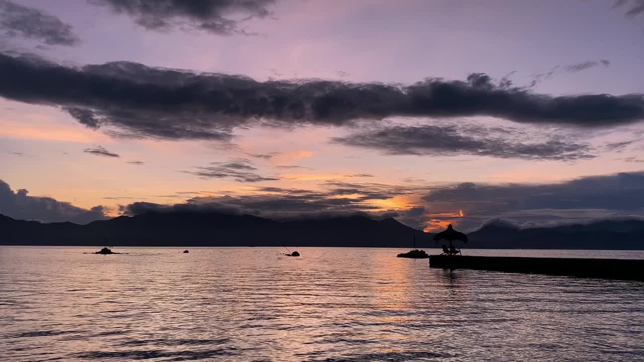 海面上的黎明映衬着热带山脉和云层视频素材