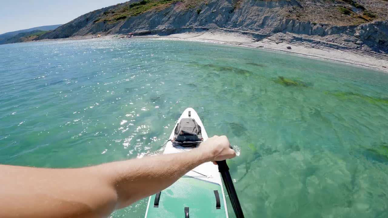 夏季站立桨板的第一人称视角。人们在透明的海面上划桨。视频素材