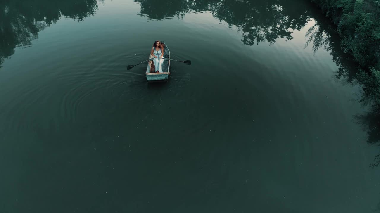 身穿白色连衣裙的女子沿着湖岸划船视频素材