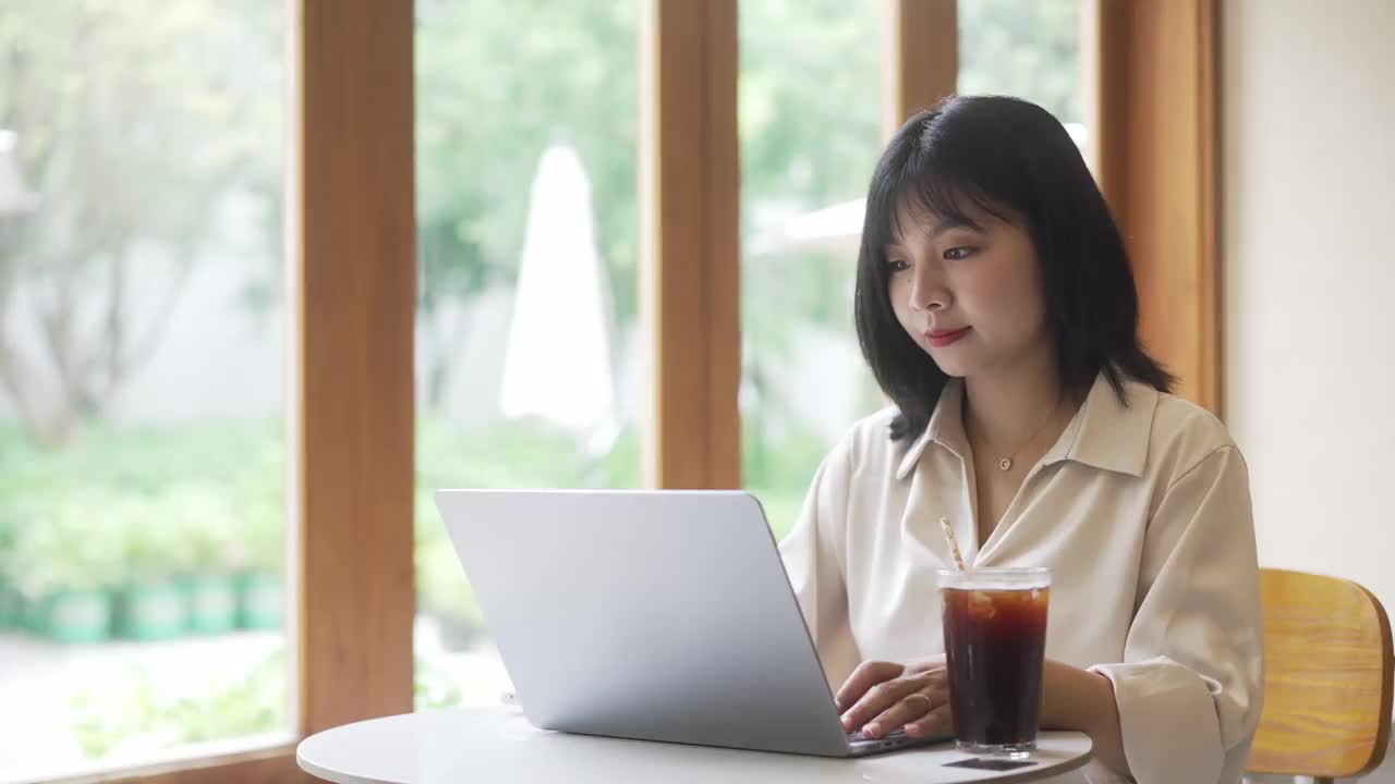 一位年轻的亚洲女商人正在咖啡店里用笔记本电脑工作视频素材