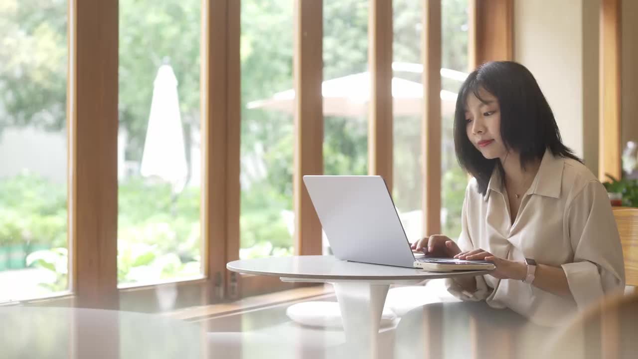 一位年轻的亚洲女商人正在咖啡店里用笔记本电脑工作视频素材