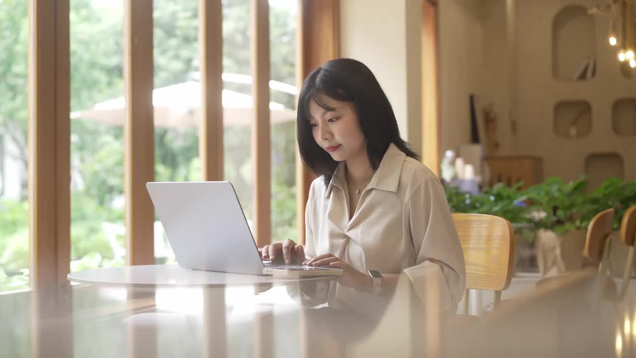 一位年轻的亚洲女商人正在咖啡店里用笔记本电脑工作视频素材