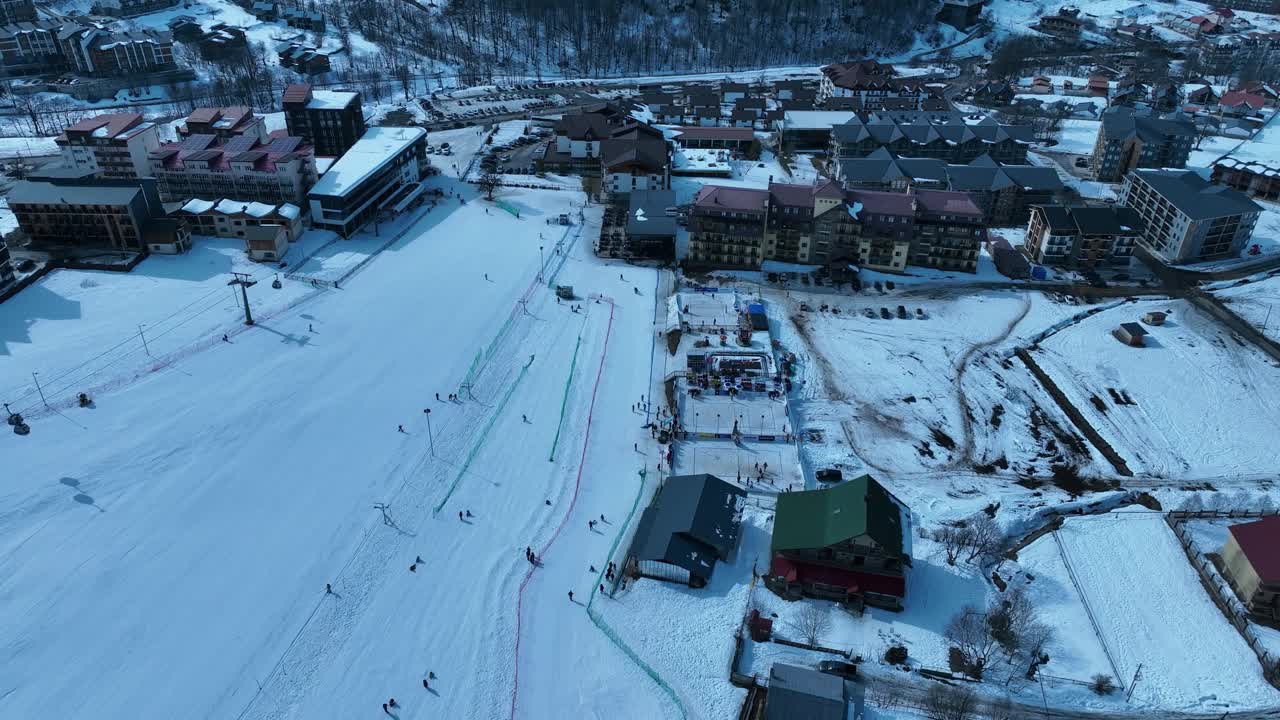 一个冰雪覆盖的滑雪胜地，滑雪者在山坡上，滑雪缆车，和一个繁华的冬季运动氛围视频素材