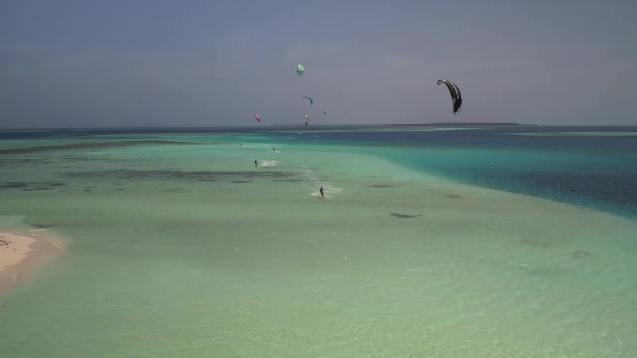 在阳光明媚的热带天堂里，风筝冲浪者在绿松石般的海浪中驰骋视频素材