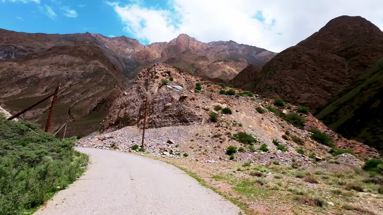 在阳光明媚的夏日山谷中穿行在破旧的路面上视频素材