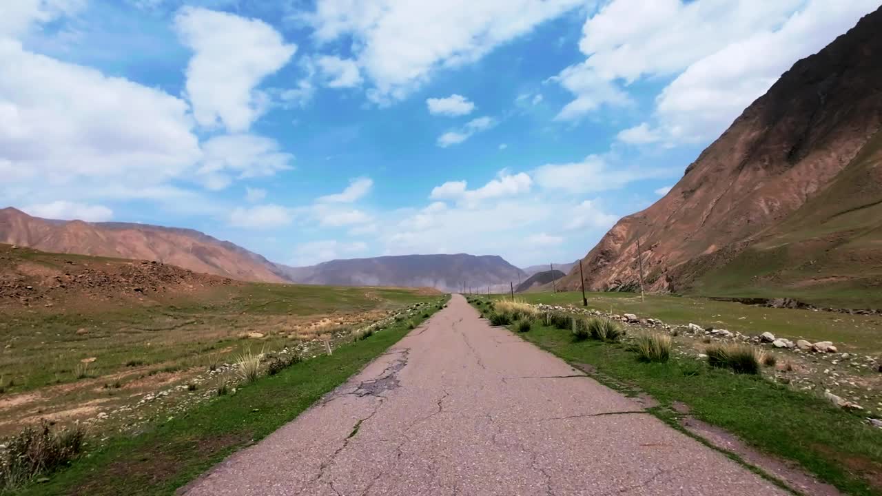 在明亮的夏日山谷中，沿着摇摇欲坠的旧路面前进视频素材