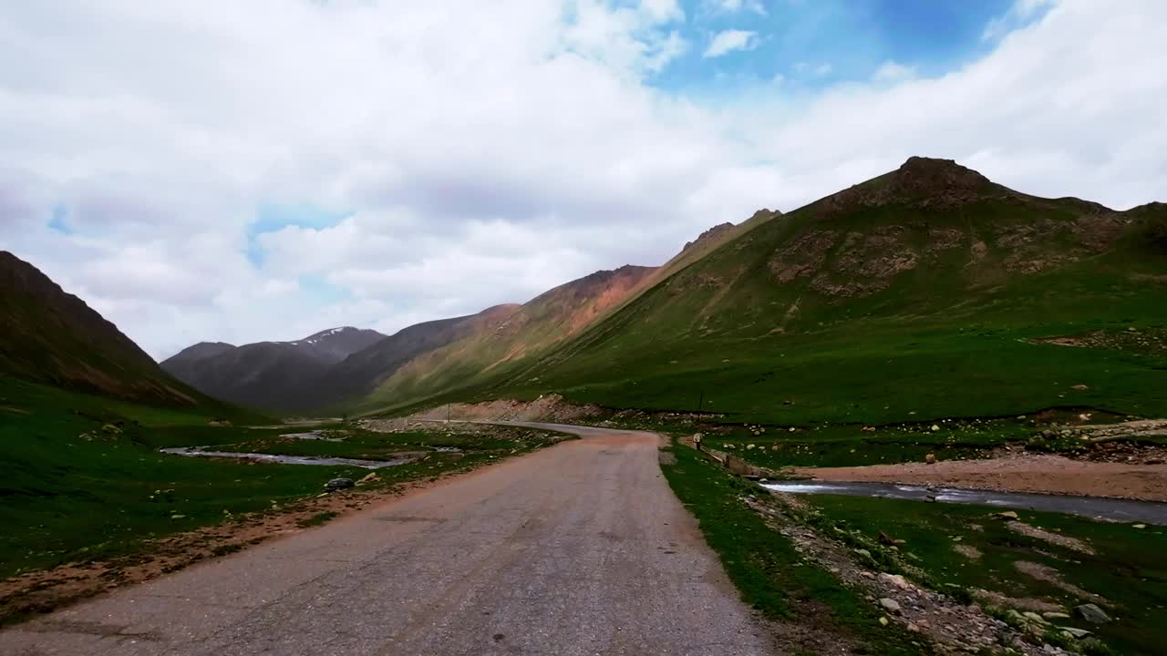 在风景如画的夏日峡谷中，青翠的河岸旁蜿蜒的柏油路视频素材