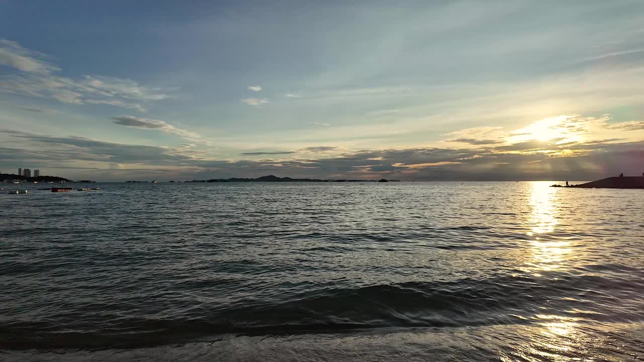 落日的天空映衬着海边的小浪。视频下载