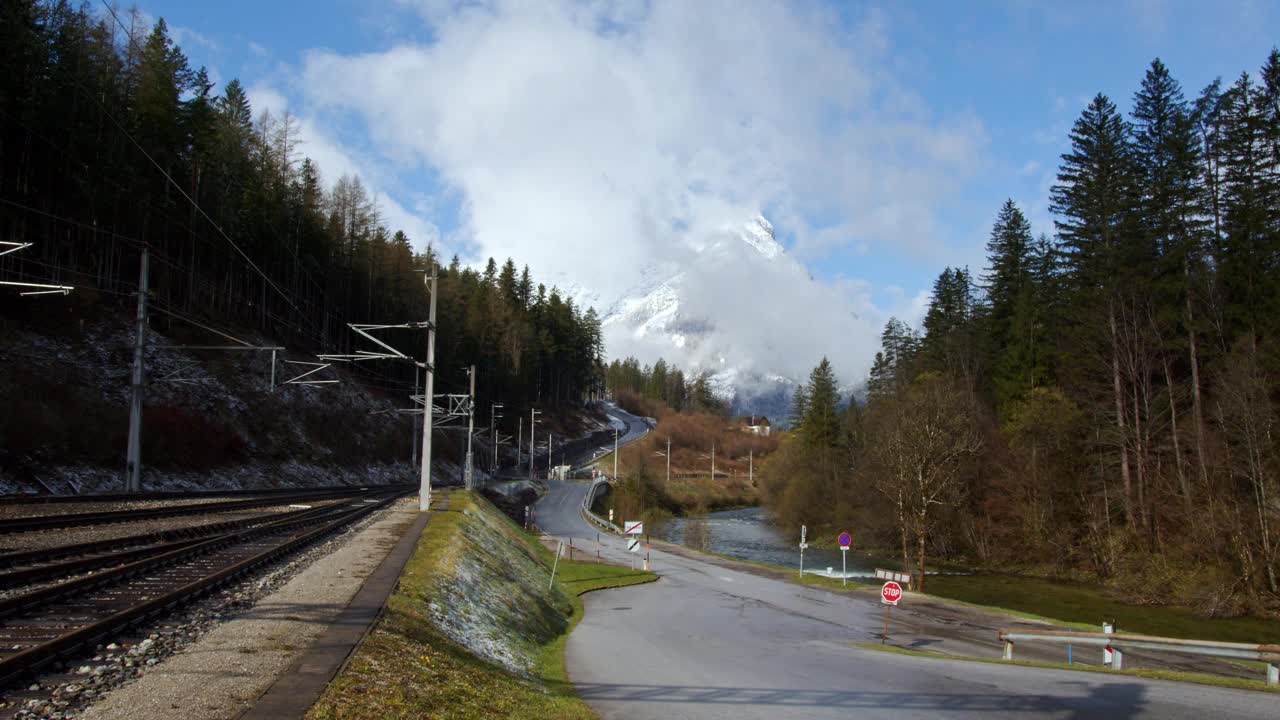 位于奥地利巴德奥西镇的火车轨道、蜿蜒的道路和以风景秀丽的山脉为背景的河流。视频素材