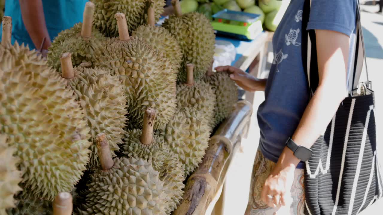 一名妇女在泰国的一个市场闻着榴莲。视频下载