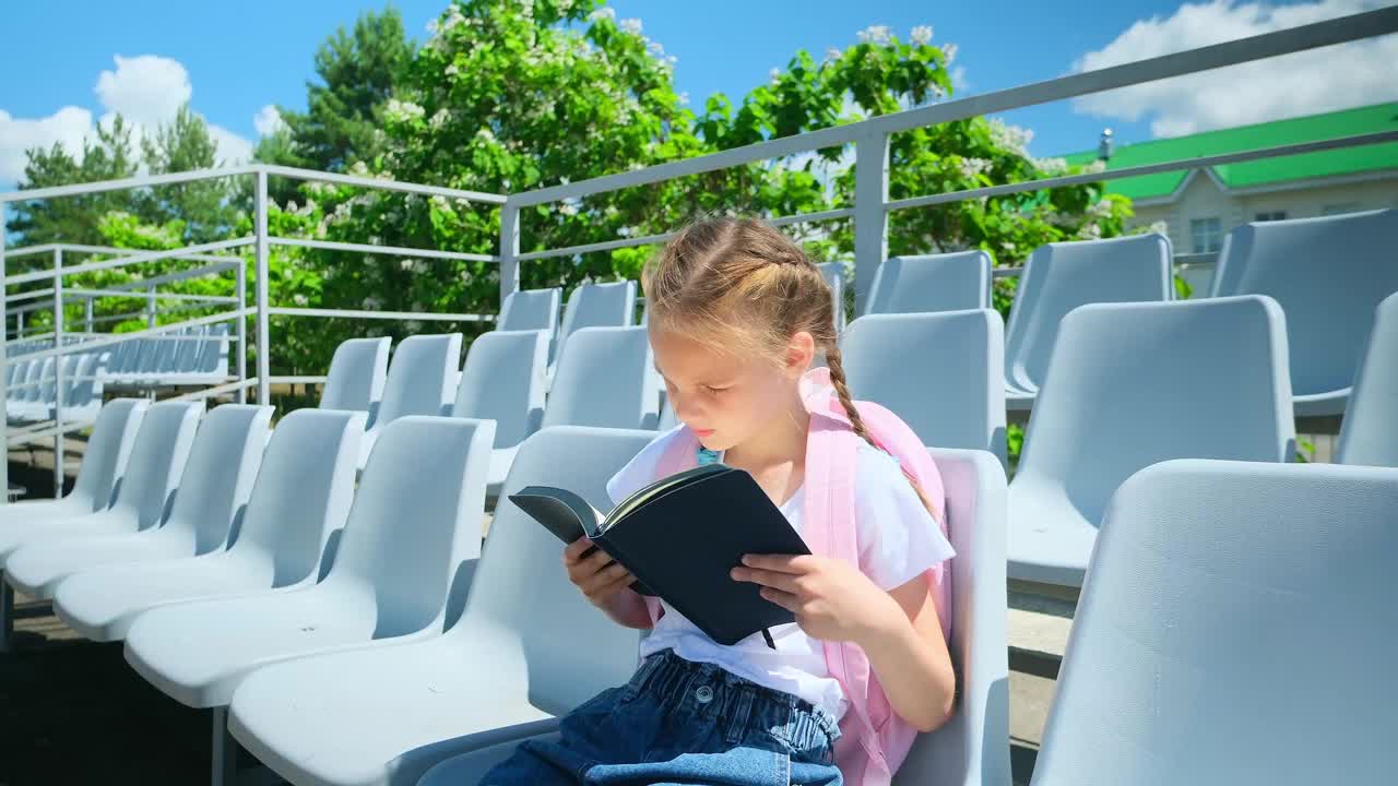 小女孩正在阅读课文，学习备课。女生做作业、学习、小学生在校园里，孩子独自集中学习聪明的课本知识视频素材