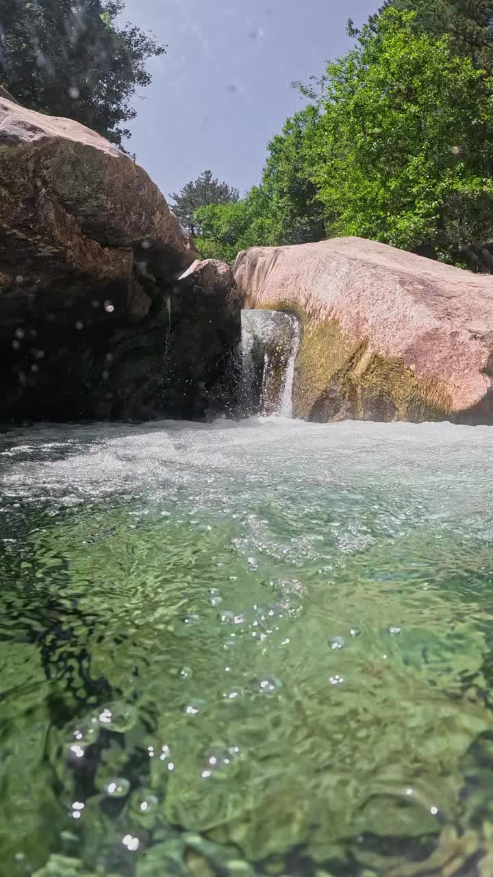 半水下的慢动作拍摄快速山涧与清澈的水。河水在石头之间流动，形成小瀑布和浴池视频素材