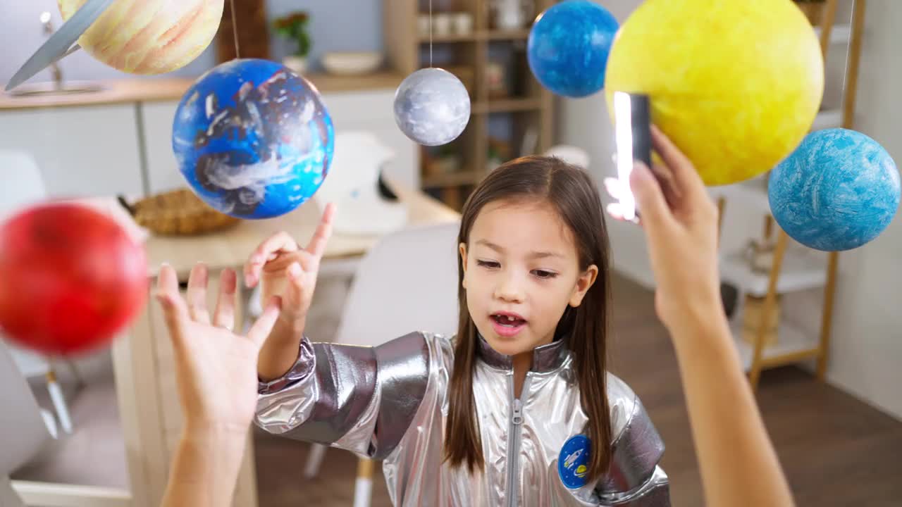 穿着太空服的女孩和她妈妈一起探索和学习行星视频下载