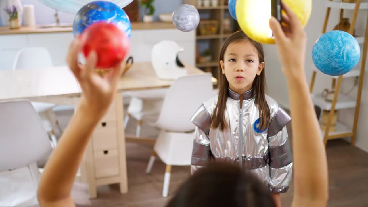 穿着太空服的女孩和她妈妈一起探索和学习行星视频素材