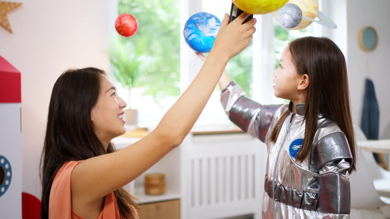 穿着太空服的女孩和她妈妈一起探索和学习行星视频素材