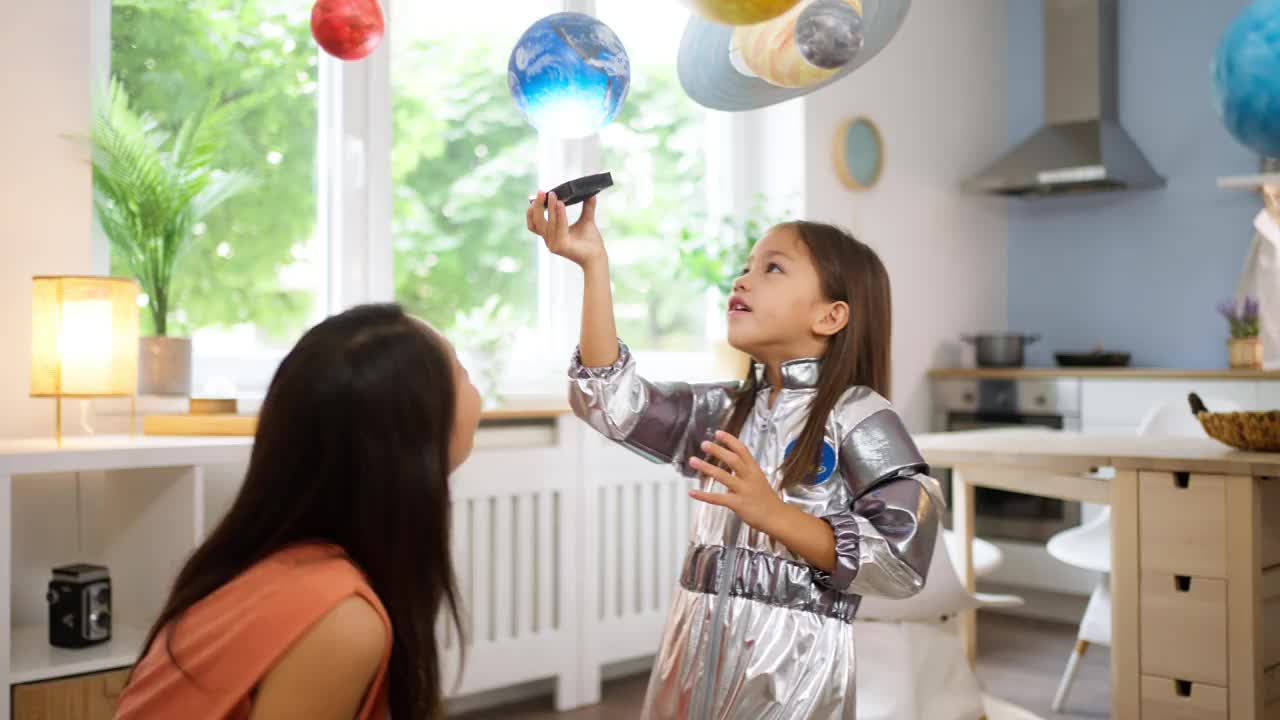 穿着太空服的女孩和她妈妈一起探索和学习行星视频素材