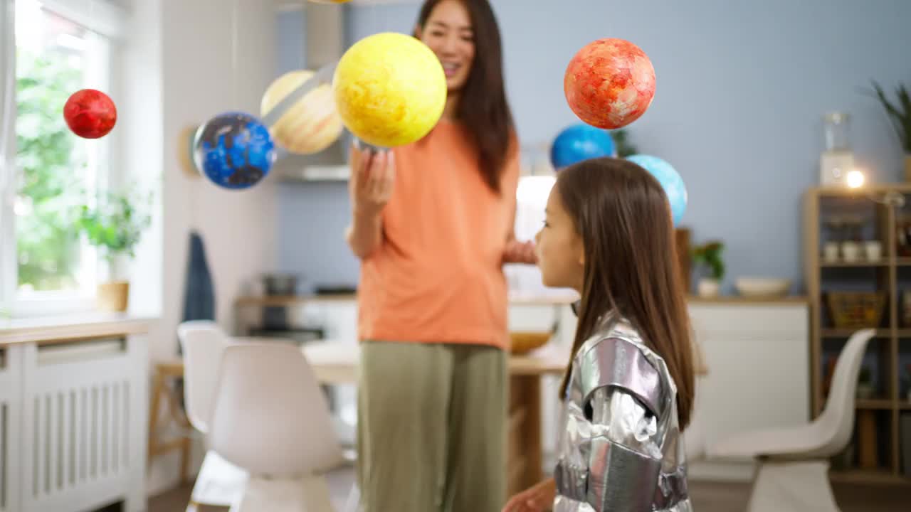 穿着太空服的女孩和她妈妈一起探索和学习行星视频下载