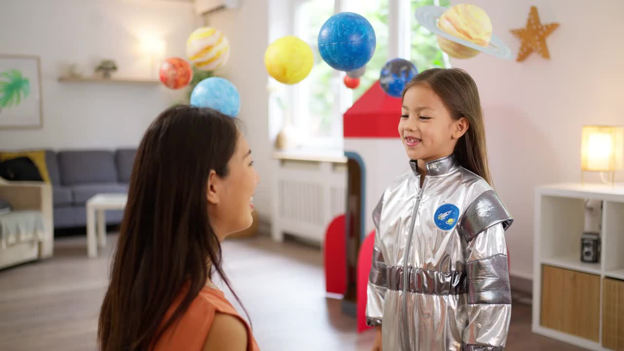 穿着太空服的女孩和妈妈在家里玩，想象着太空旅行。视频素材