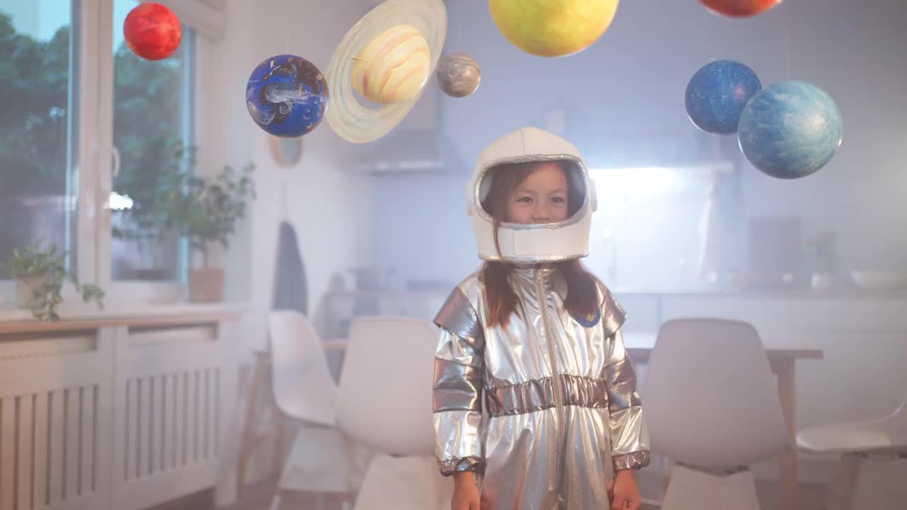 穿着太空服的女孩在家里玩耍，探索和学习行星，想象太空旅行。视频素材