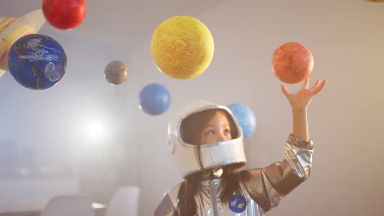 穿着太空服的女孩在家里玩耍，探索和学习行星，想象太空旅行。视频素材