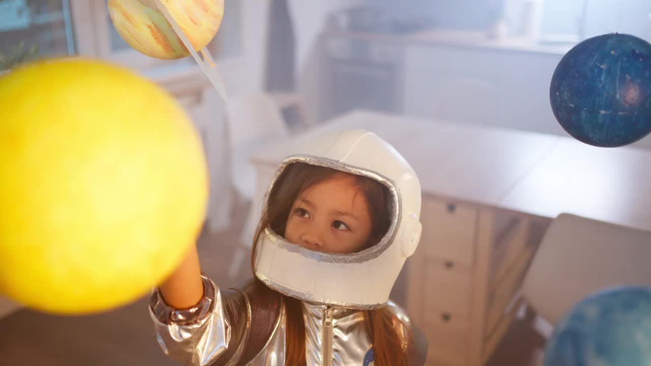 穿着太空服的女孩在家里玩耍，探索和学习行星，想象太空旅行。视频素材