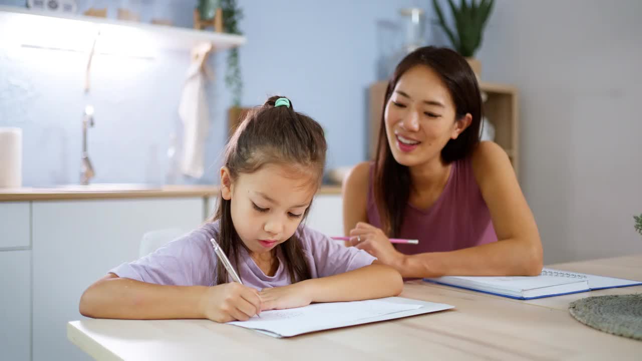 一个女学生在她在家工作的妈妈旁边做作业视频素材