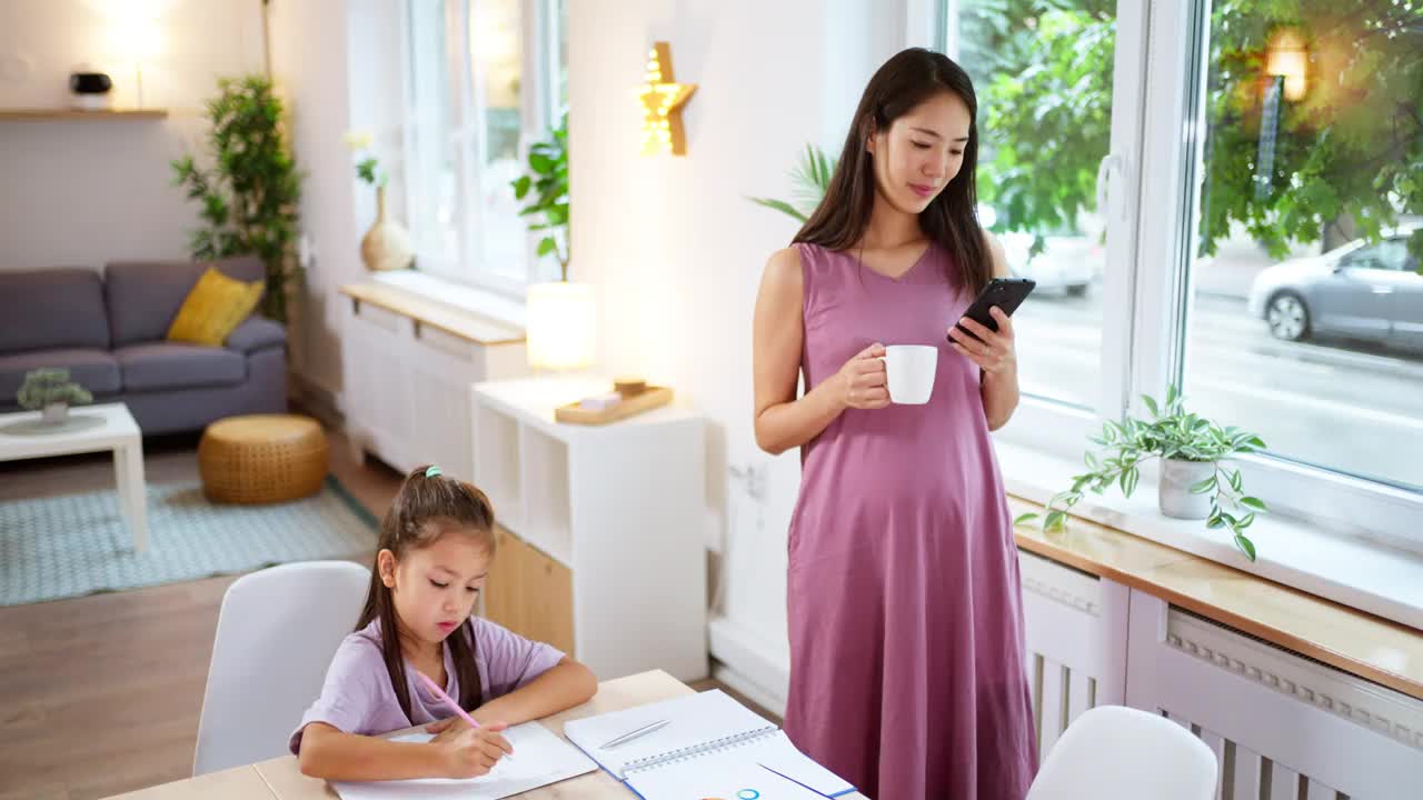 一个女学生在她怀孕在家工作的妈妈旁边做作业视频素材