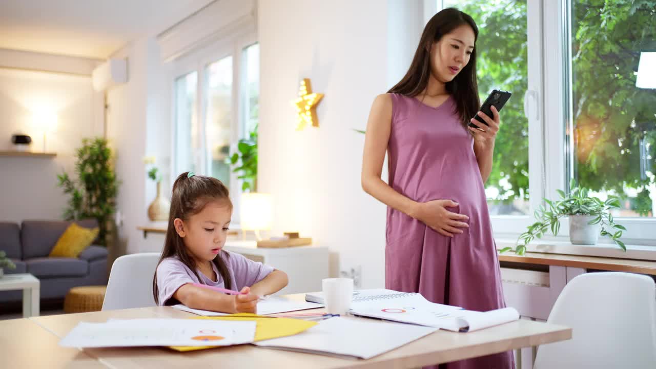 一个女学生在她怀孕在家工作的妈妈旁边做作业视频下载