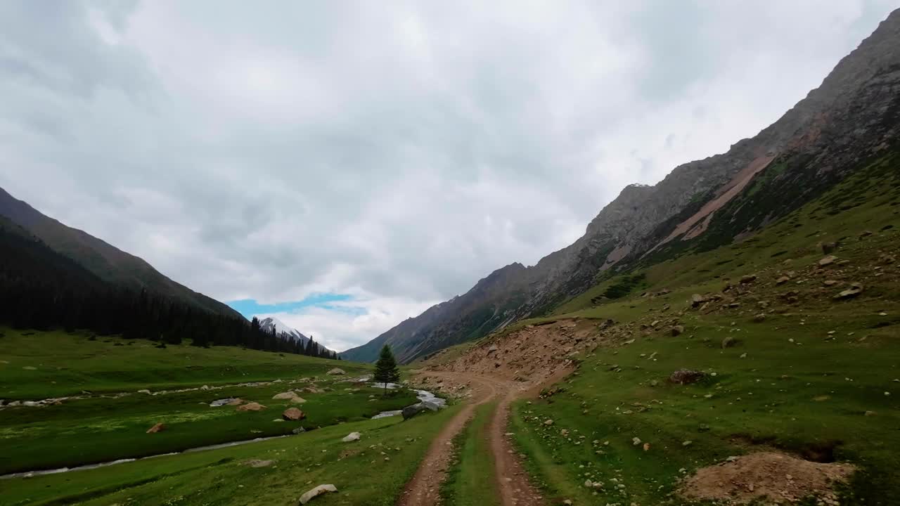 在多云的夏日峡谷中，驾车行驶在风景如画的山间河岸上视频素材