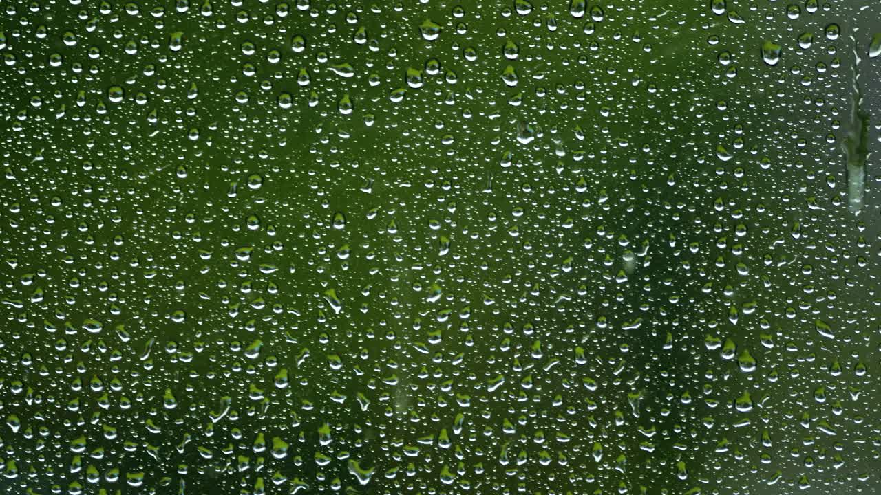 雨滴落在玻璃上的特写视频。深黑色背景。纯净和新鲜。视频素材