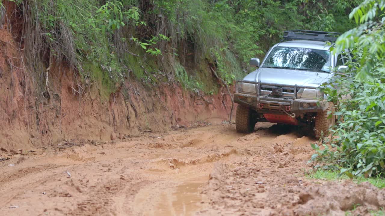 在越野道路上奔跑的汽车，在自然小路上溅起的泥浆。在泥泞的道路上越野旅行。越野车越野四驱车穿过泥泞的水坑，越野赛道的道路，与大水花。视频素材