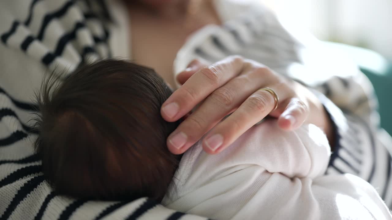 母亲安抚新生婴儿的特写，强调在宁静和充满爱的家庭环境中温柔和养育的纽带视频素材