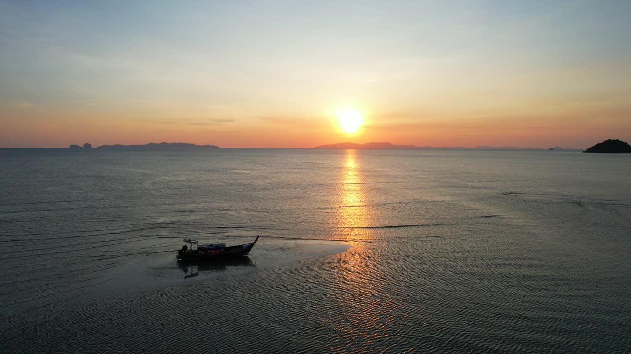 在亚洲泰国南部沙敦省的白孟海滩，一艘长尾船在海上欣赏日落视频素材