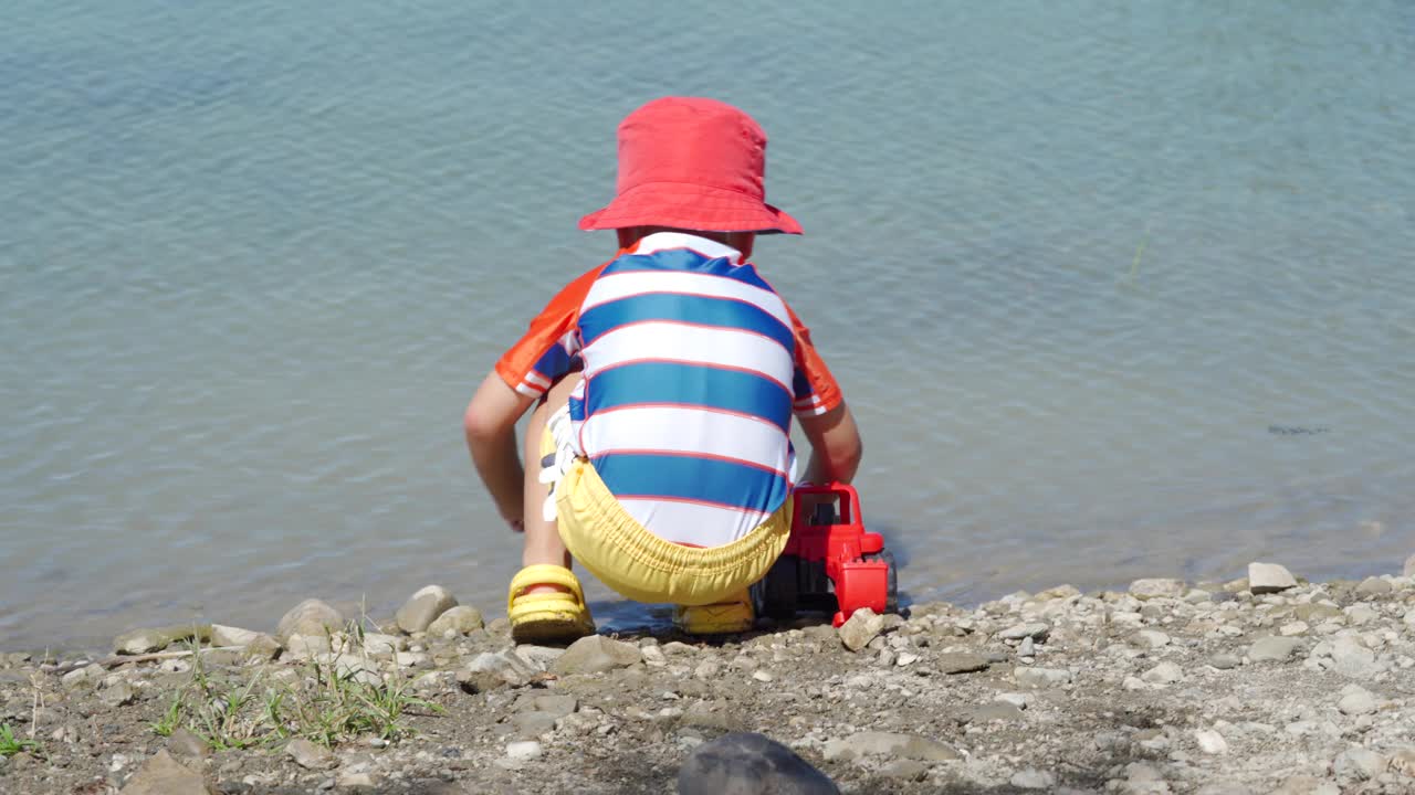 夏日里，穿着防晒服的小孩在湖边玩耍。视频素材