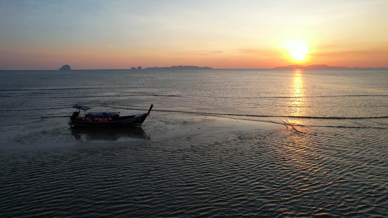 在亚洲泰国南部沙敦省的白孟海滩，一艘长尾船在海上欣赏日落视频下载