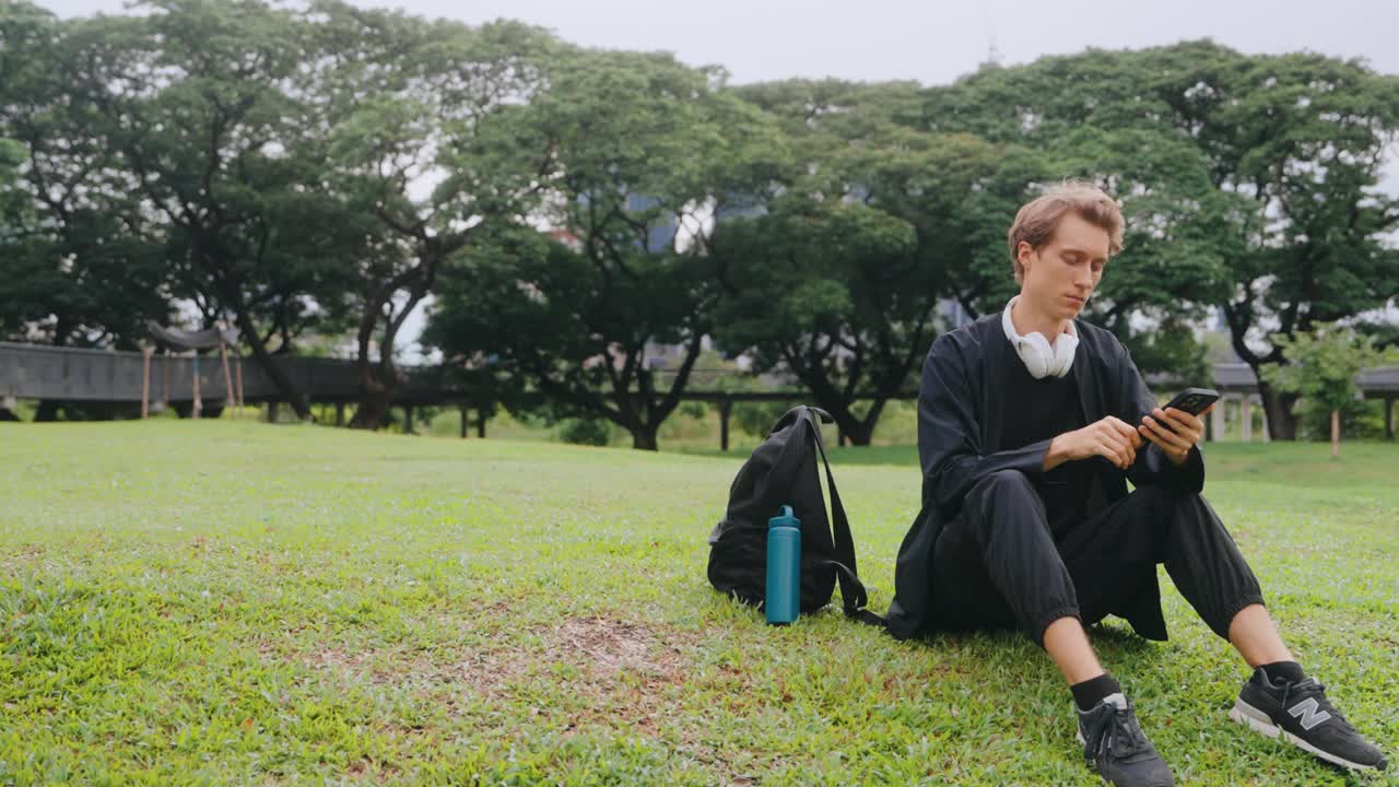 男子带着智能手机和耳机在户外放松视频下载