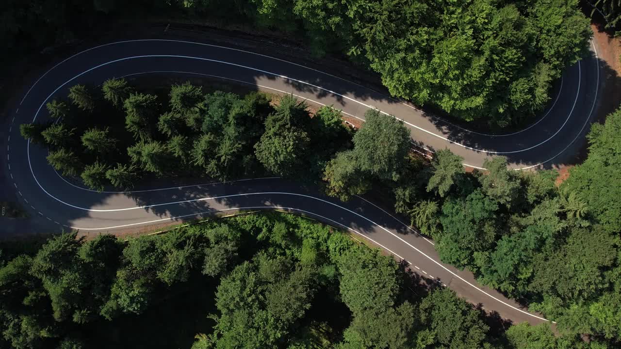 弯弯曲曲的柏油路在山上。鸟瞰图的道路穿过山和绿色的森林。视频素材