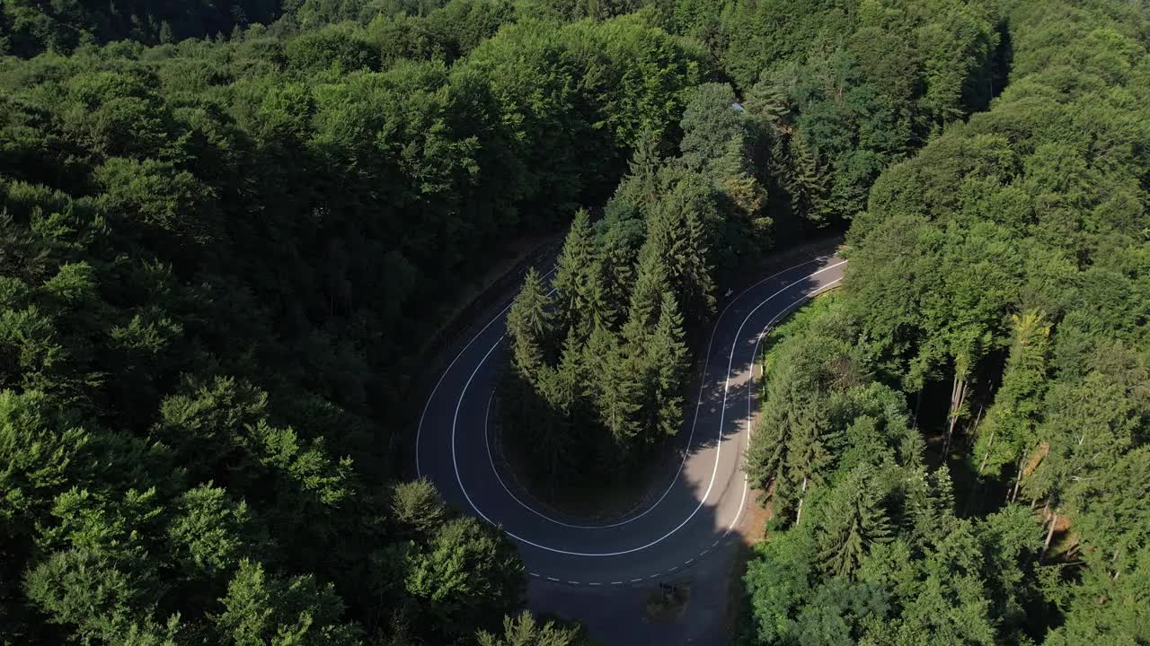 弯弯曲曲的柏油路在山上。鸟瞰图的道路穿过山和绿色的森林。视频素材