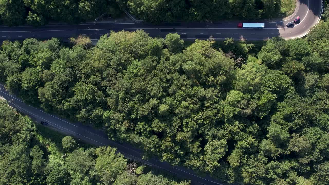 弯弯曲曲的柏油路在山上。鸟瞰图的道路穿过山和绿色的森林。视频下载