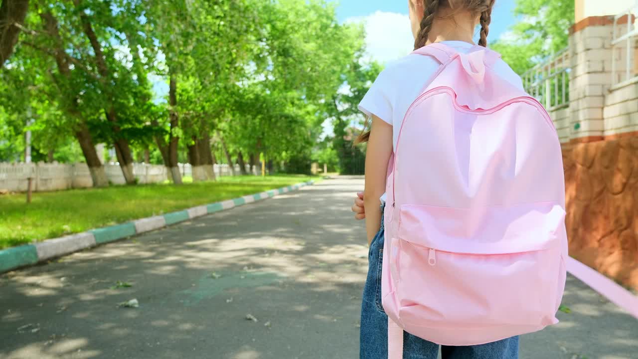 回到学校。一个背着背包的小女孩沿着马路穿过校园往学校跑。教育孩子的理念。一个背着背向背包的小孩跑向学校视频素材