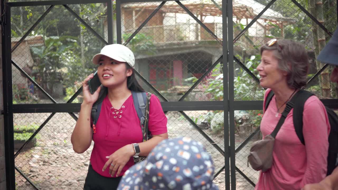 一群不同的旅行者中的年轻女子在电话中与民宿主人打招呼视频素材