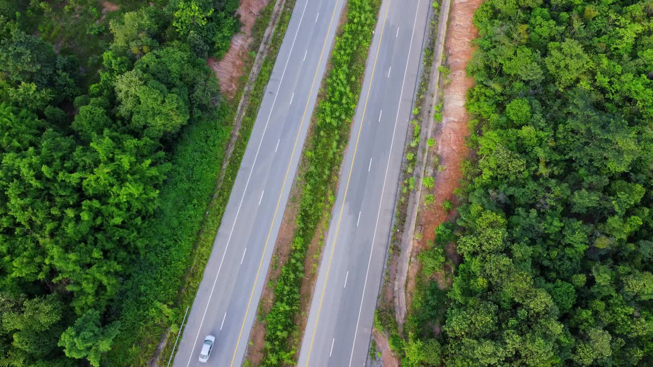 鸟瞰图乡村柏油路与汽车和绿色的森林。行驶在绿色森林之间的道路上。视频素材