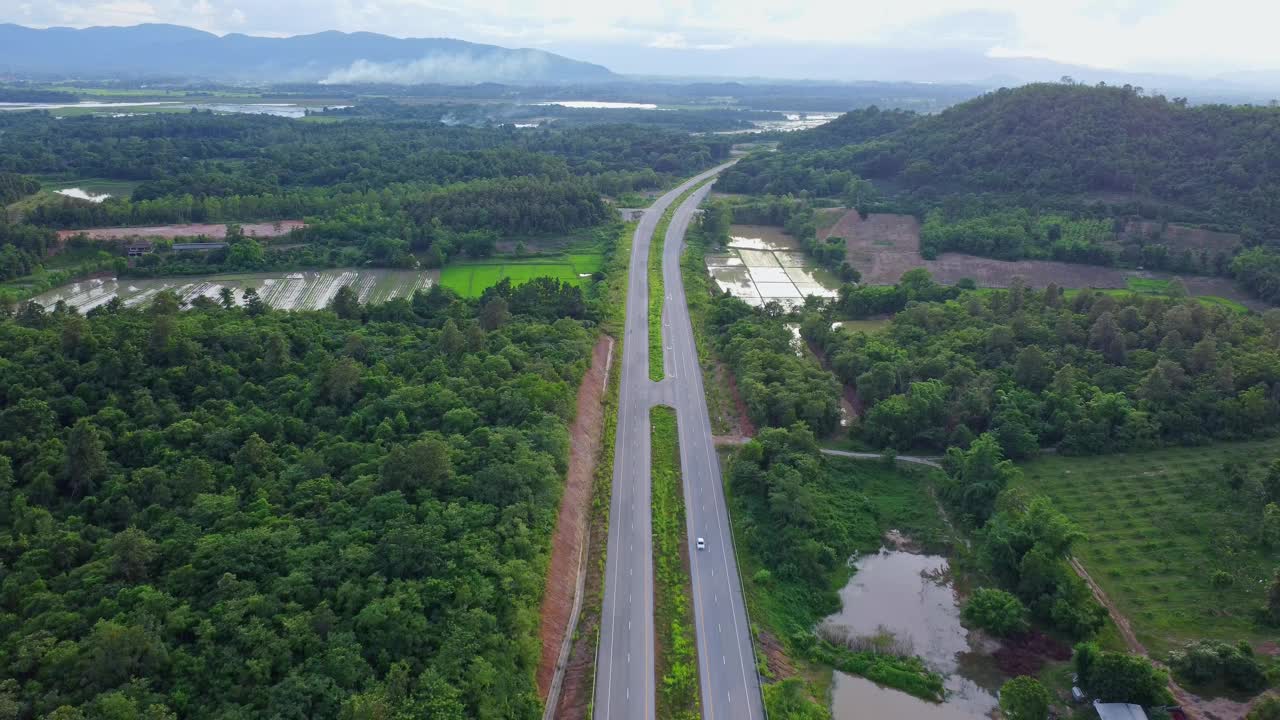 鸟瞰图乡村柏油路与汽车和绿色的森林。行驶在绿色森林之间的道路上。视频素材