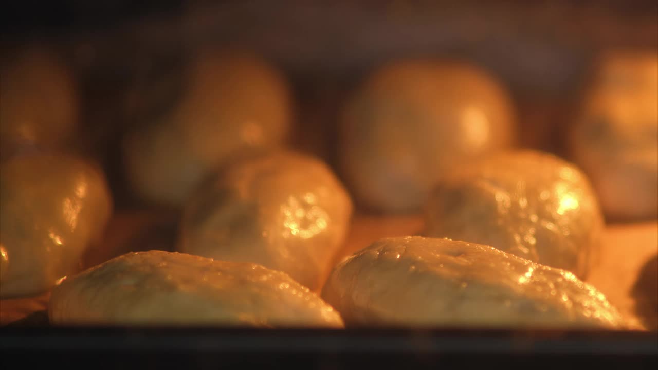 面包卷在烤箱里烤着。新鲜出炉的面包特写镜头。食物准备和烘焙概念，时间间隔视频下载