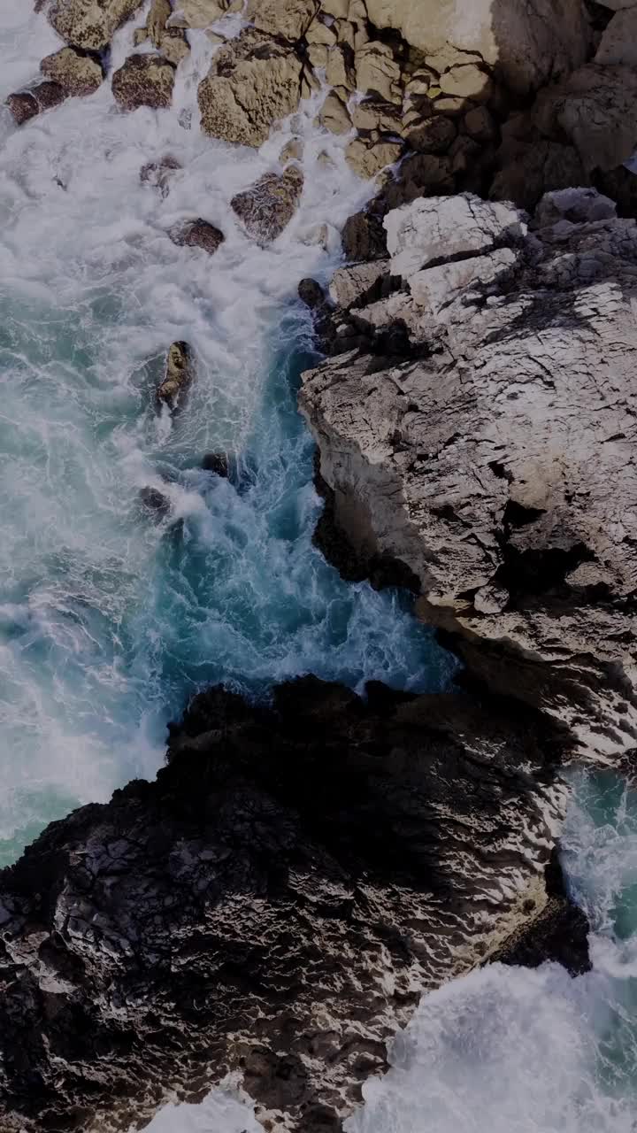 鸟瞰图的海浪冲击悬崖在金丘海滩，卡斯凯伊斯，葡萄牙。垂直视频视频素材